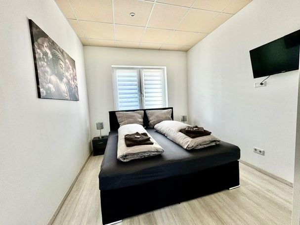 Modernes Schlafzimmer mit Doppelbett und Fernseher