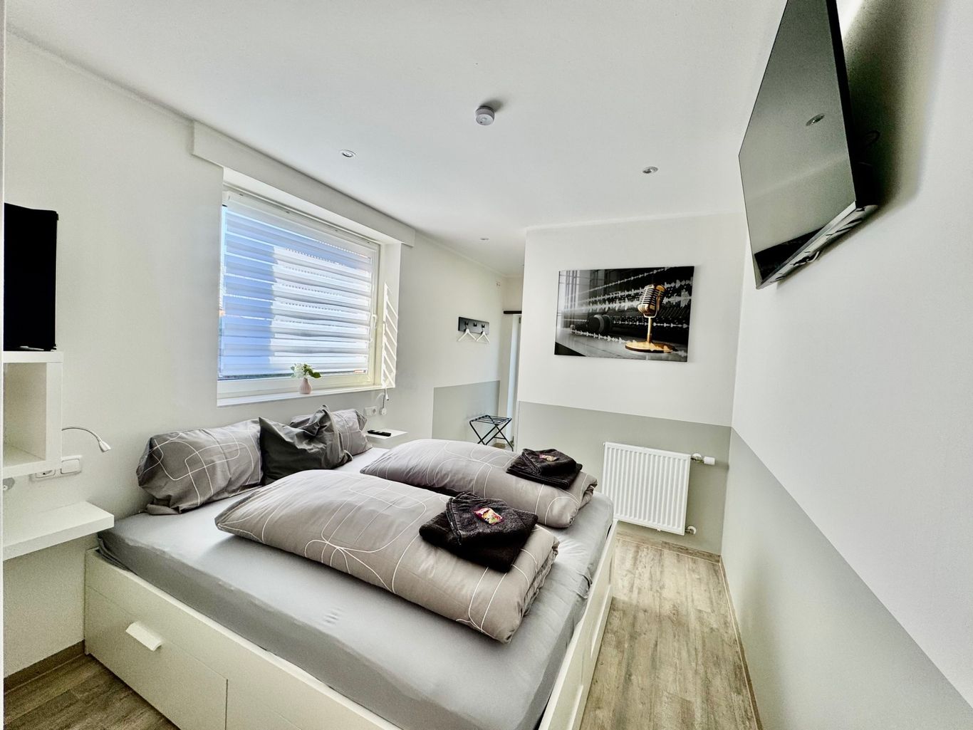 Stilvoll eingerichtetes Gästezimmer mit gemütlichem Doppelbett, Wand-TV, modernem Design und Fenster für viel Tageslicht.