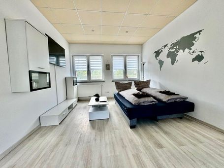 Geräumiges, stilvoll eingerichtetes Studio mit einem gemütlichen Boxspringbett, einer modernen Wohnwand mit Flachbildfernseher