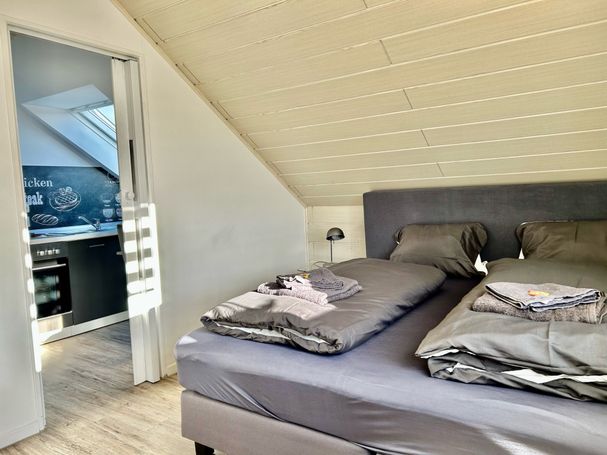 Gemütliches Dachgeschoss-Schlafzimmer mit Blick in die Küche