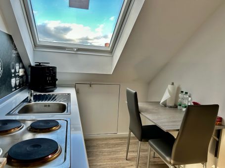 Gemütliche Dachgeschoss-Küche mit großem Dachfenster, das für viel Tageslicht sorgt. 